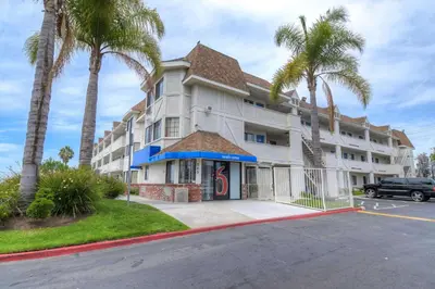 a large white building with palm trees in front of it at Motel 6-Chula Vista, CA - San Diego in Chula Vista