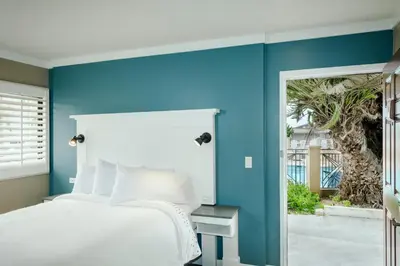 a bedroom with blue walls and a white bed and a door at Pacific Shores Inn in San Diego