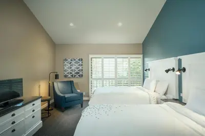 a bedroom with two beds and a blue chair at Pacific Shores Inn in San Diego