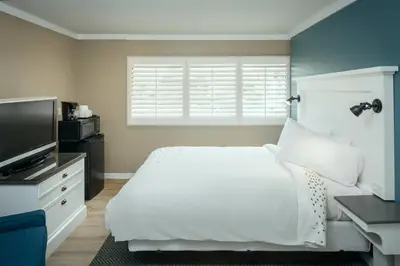 a bedroom with a white bed and a flat screen tv at Pacific Shores Inn in San Diego