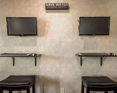 a computer monitor on a wall with two stools at Quality Inn Temecula Valley Wine Country in Temecula