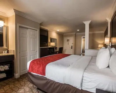 a hotel room with a large bed with a red blanket at Comfort Suites San Clemente Beach in San Clemente