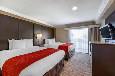 a hotel room with two beds and a flat screen tv at Comfort Suites San Clemente Beach in San Clemente