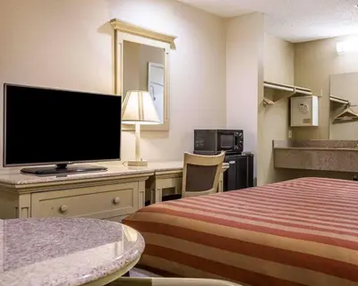 a hotel room with a bed and a desk with a television at Rodeway Inn Santee San Diego East in Santee