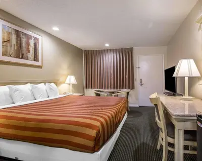 a hotel room with a large bed and a desk at Rodeway Inn Santee San Diego East in Santee