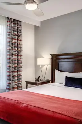 a bedroom with a large bed with a red blanket at Ayres Suites Mission Viejo - Lake Forest in Mission Viejo