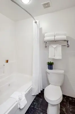 a white bathroom with a toilet and a bath tub at Ayres Suites Mission Viejo - Lake Forest in Mission Viejo
