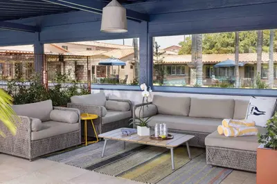 a patio with couches and a table and windows at La Jolla Beach & Tennis Club in San Diego