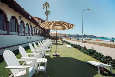 a row of chairs and an umbrella next to a building at La Jolla Shores Hotel in San Diego