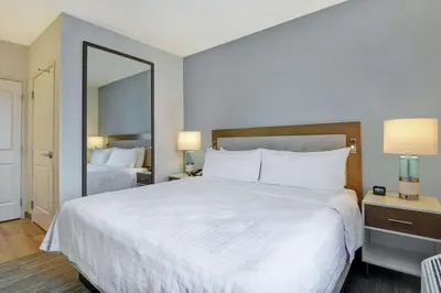a hotel room with a large white bed and a mirror at Homewood Suites By Hilton Chula Vista Eastlake in Chula Vista