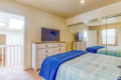 a bedroom with two beds and a tv and a dresser at Ocean Beach Cliffs Sanctuary Oceanfront in San Diego