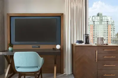 a living room with a tv and a desk with a chair at Carte Hotel San Diego Downtown, Curio Collection By Hilton in San Diego