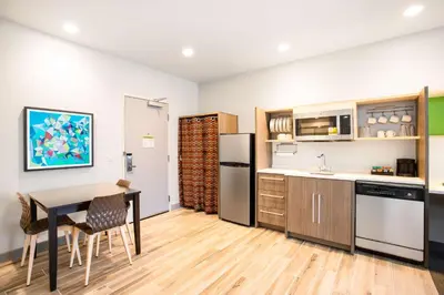 a kitchen with a table and a refrigerator at Home2 Suites By Hilton Carlsbad, Ca in Carlsbad