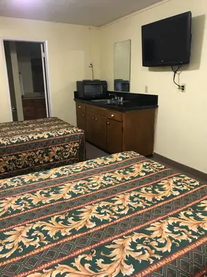a hotel room with two beds and a flat screen tv at Hacienda Motel in Escondido