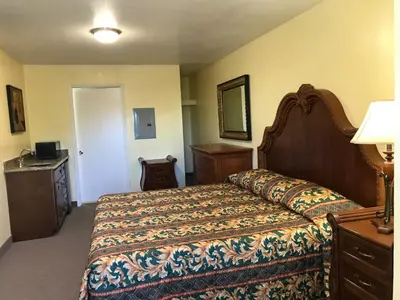 a bedroom with a bed and a dresser and a mirror at Hacienda Motel in Escondido