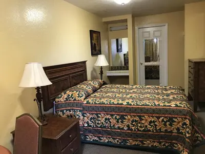 a bedroom with a bed and a table and lamps at Hacienda Motel in Escondido