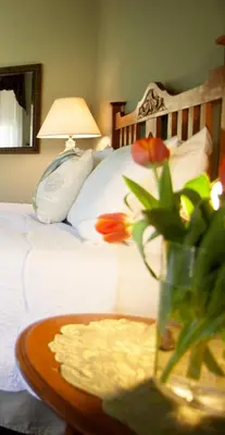 a table with a vase with flowers on a bed at Julian Lodge in Julian