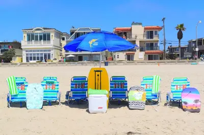 a group of chairs and an umbrella on the beach at Luv Oceanside Views-1 House to Beach, Boardwalk and Waves-Spacious Rooftop Sun Deck-Plus King Beds too! in San Diego