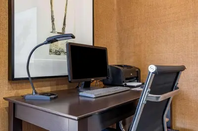 a desk with a computer and a lamp on it at The Encinitan Hotel & Suites in Encinitas