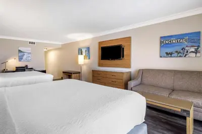 a hotel room with two beds and a couch at The Encinitan Hotel & Suites in Encinitas