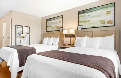 two beds in a hotel room with white sheets at Extended Stay America Suites - San Diego - Carlsbad Village by the Sea in Carlsbad