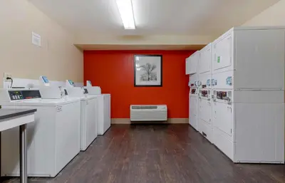 a room with white washing machines and an orange wall at Extended Stay America Suites - San Diego - Carlsbad Village by the Sea in Carlsbad