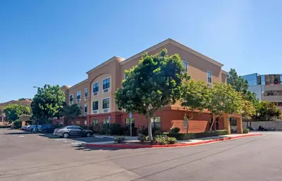 a building with a tree in front of a street at Extended Stay America Suites - San Diego - Mission Valley - Stadium in San Diego