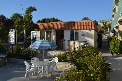 a table and chairs with an umbrella in front of a house at Moonlight Beach Motel in Encinitas