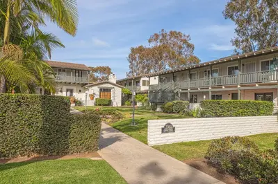 a row of apartment buildings with trees and a sidewalk at Heart of the Village in Carlsbad