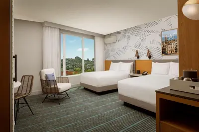 a hotel room with two beds and a chair at The Monsaraz San Diego, Tapestry Collection By Hilton in San Diego
