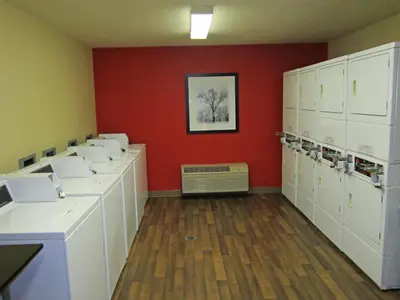 a laundry room with white cabinets and a red wall at Extended Stay America Suites - Orange County - John Wayne Airport in Newport Beach