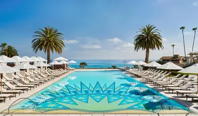 a swimming pool with lounge chairs and the ocean at Montage Laguna Beach in Laguna Beach