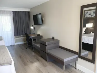 a hotel room with a desk and a bed and a mirror at Econo Lodge Lake Elsinore Casino in Lake Elsinore