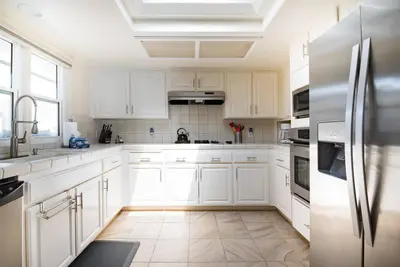 a kitchen with white cabinets and a stainless steel refrigerator at Luxury Penthouse with Elevator - Sleeps 10+ - Family Friendly Sun / Surf / Sand in San Diego