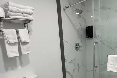 a bathroom with a shower and white towels at Super 8 by Wyndham Oceanside Downtown in Oceanside