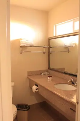 a bathroom with a sink and a mirror and a toilet at Menifee Inn in Menifee