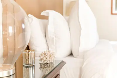 a bed with white pillows and a table with a vase at Four Seasons Residence Club Aviara in Carlsbad