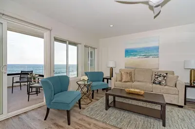 a living room with a couch and chairs and the ocean at Ocean Villas Beach Front in Carlsbad