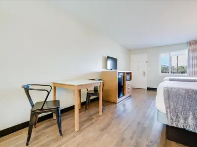 a bedroom with a desk and a bed and a table and chairs at The Atwood Hotel San Diego - SeaWorld/Zoo in San Diego