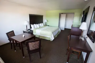 a hotel room with a bed and a table and chairs at Days Inn by Wyndham Oceanside in Oceanside