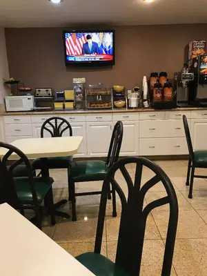 a restaurant with tables and chairs and a tv on the wall at Days Inn by Wyndham Oceanside in Oceanside