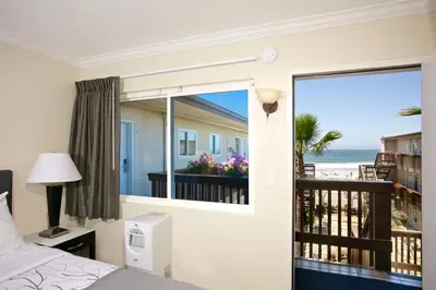 a bedroom with a bed and a balcony with the ocean at Ocean Beach Hotel in San Diego