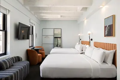 a hotel room with two beds and a couch at The Guild Hotel, San Diego Downtown, a Tribute Portfolio Hotel in San Diego