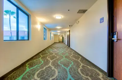 an empty hallway with a carpeted floor in an office building at Holiday Inn Express Hotel & Suites Carlsbad Beach by IHG in Carlsbad