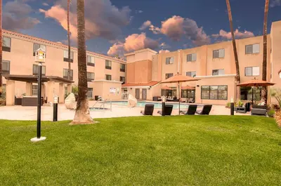 a building with a courtyard with chairs and umbrellas at Holiday Inn Express Hotel & Suites Carlsbad Beach by IHG in Carlsbad