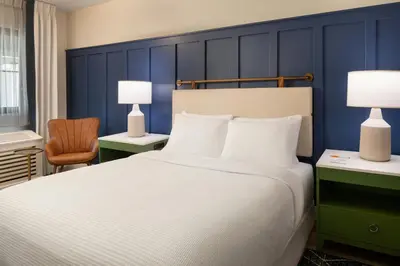 a bedroom with a large bed and a blue wall at Tiller House, Laguna Hills, a Tribute Portfolio Hotel in Laguna Hills