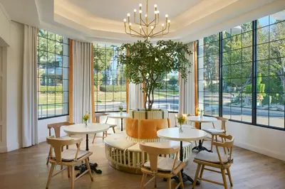 a restaurant with tables and chairs and large windows at Tiller House, Laguna Hills, a Tribute Portfolio Hotel in Laguna Hills