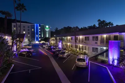 a parking lot with cars parked in front of buildings at night at Hotel Iris - Mission Valley-San Diego Zoo-SeaWorld in San Diego