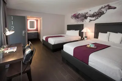 a hotel room with two beds and a desk at Hotel Iris - Mission Valley-San Diego Zoo-SeaWorld in San Diego