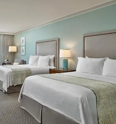 a hotel room with two beds with white sheets at Loews Coronado Bay Resort in San Diego